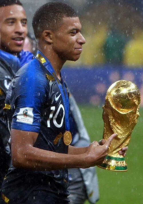 Kylian Mbappé holding the FIFA World Cup trophy in 2018 — one of the fastest-rising fortunes in football