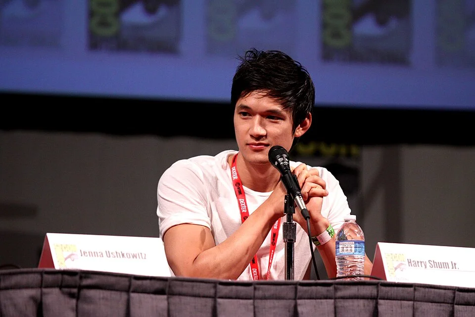 Harry Shum Jr. at a Glee panel at Comic-Con beside Jenna Ushkowitz's name card