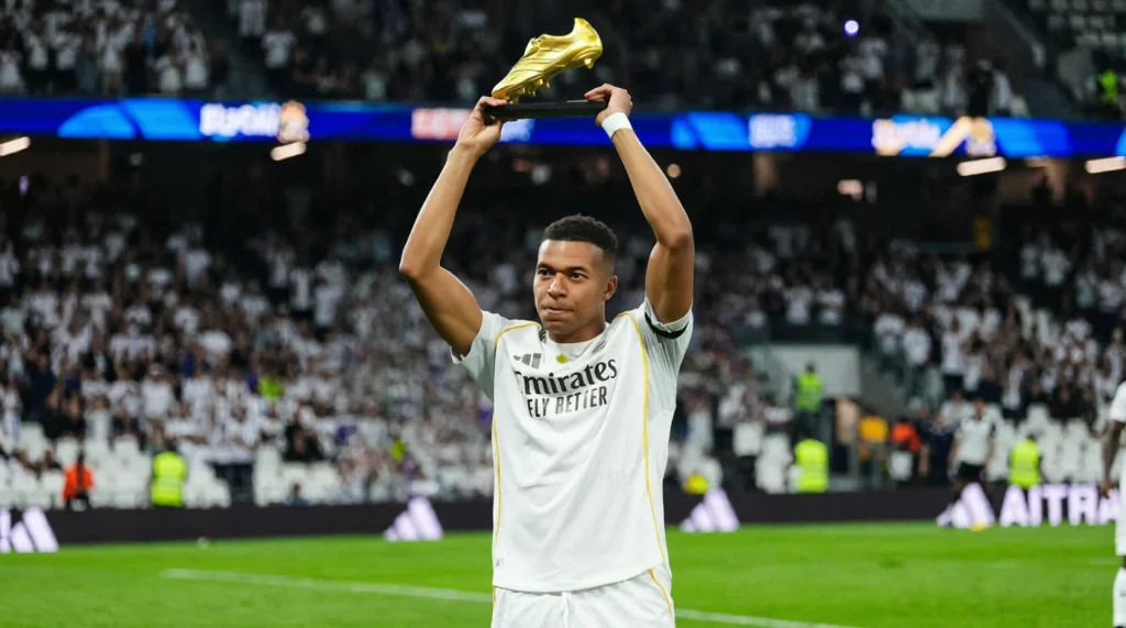 Kylian Mbappé in the Real Madrid kit holding up a Golden Boot trophy