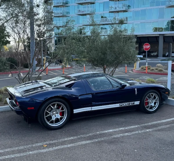 Blue and black 2005 Ford GT with white racing stripes, modified to produce over 700 horsepower, parked in a lot
