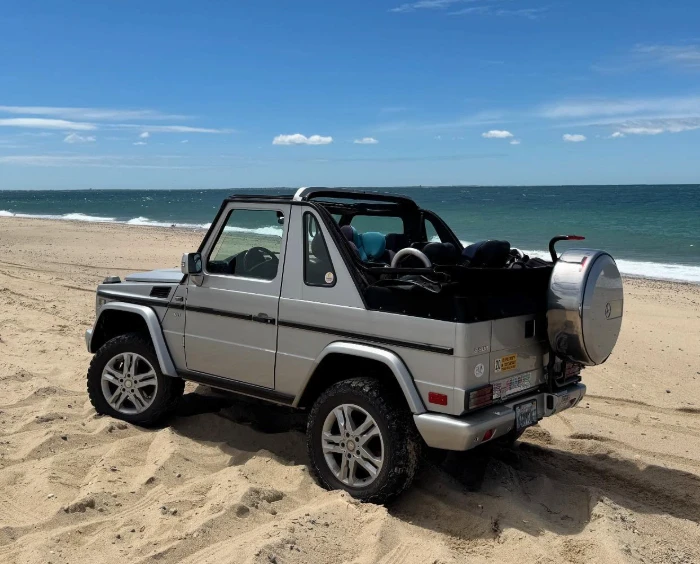 Silver 1999 Mercedes-Benz G500 Cabriolet with soft-top down on a beach, Doug DeMuro's Barbie Jeep