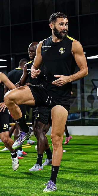 Karim Benzema in an Al-Ittihad jersey standing on the pitch