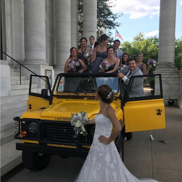 Doug DeMuro's wife Joanna in her wedding dress with the wedding party on a yellow Land Rover Defender, July 2017