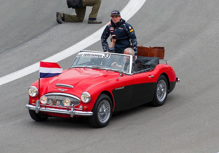 Max Verstappen in classic Austin-Healey during drivers' parade with Dutch flag at Red Bull Racing event