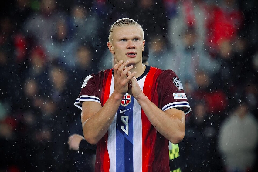 Erling Haaland applauding Norway supporters in the rain wearing the national team's home kit