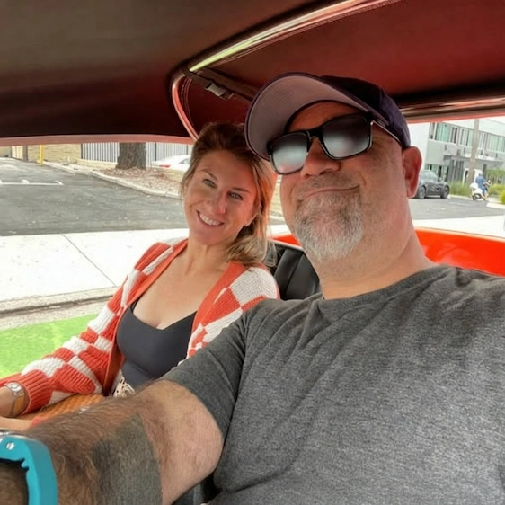 Matt Farah and his wife Hanna smiling together in a car