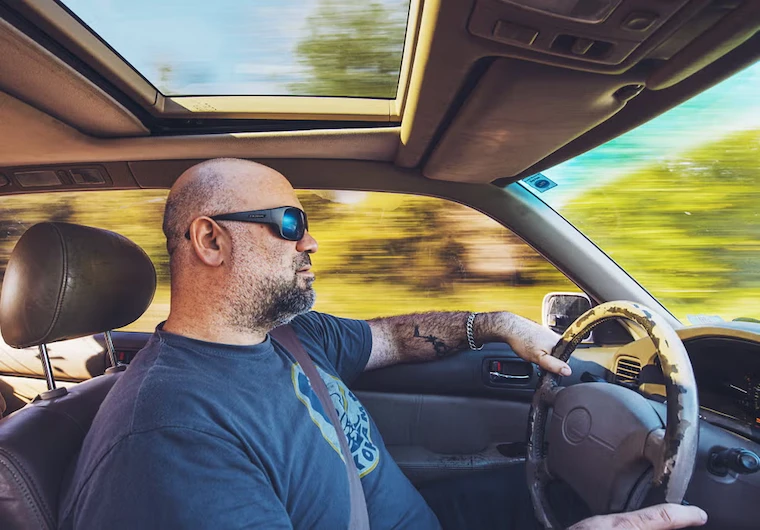 Matt Farah at the wheel of his Million Mile Lexus, a 1996 LS400, with a worn steering wheel and motion-blurred scenery